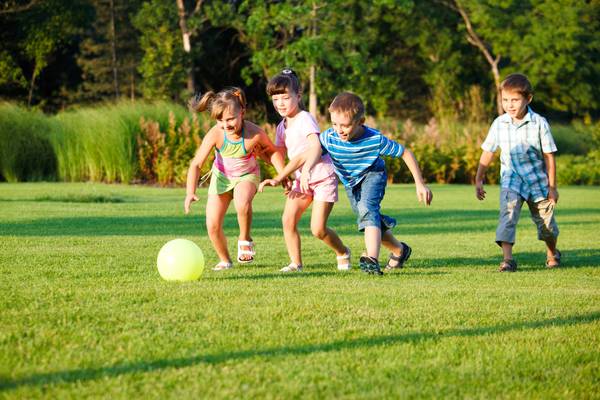 Kids playing football on greenery play ground