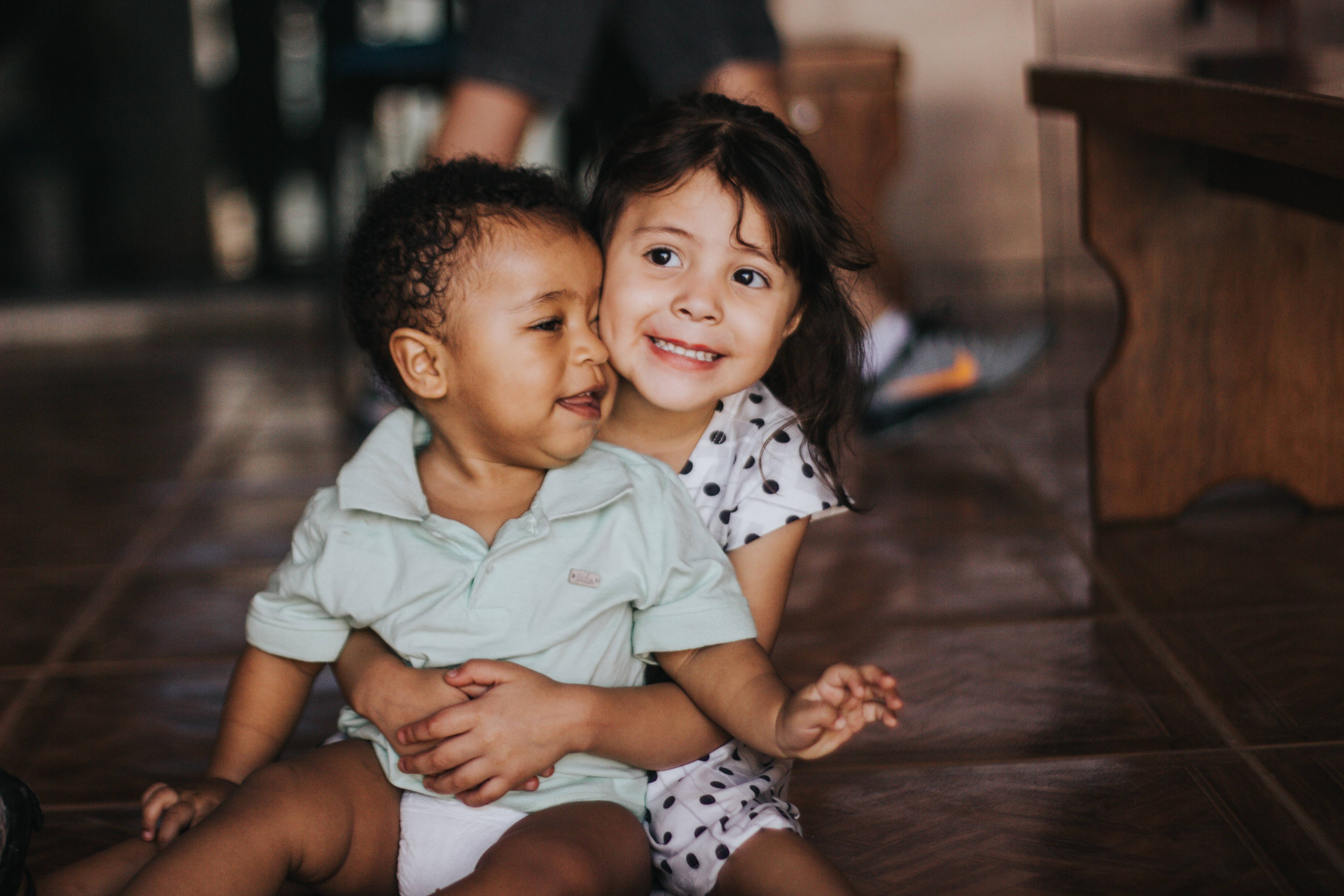 Smiling girl with younger boy inside the room