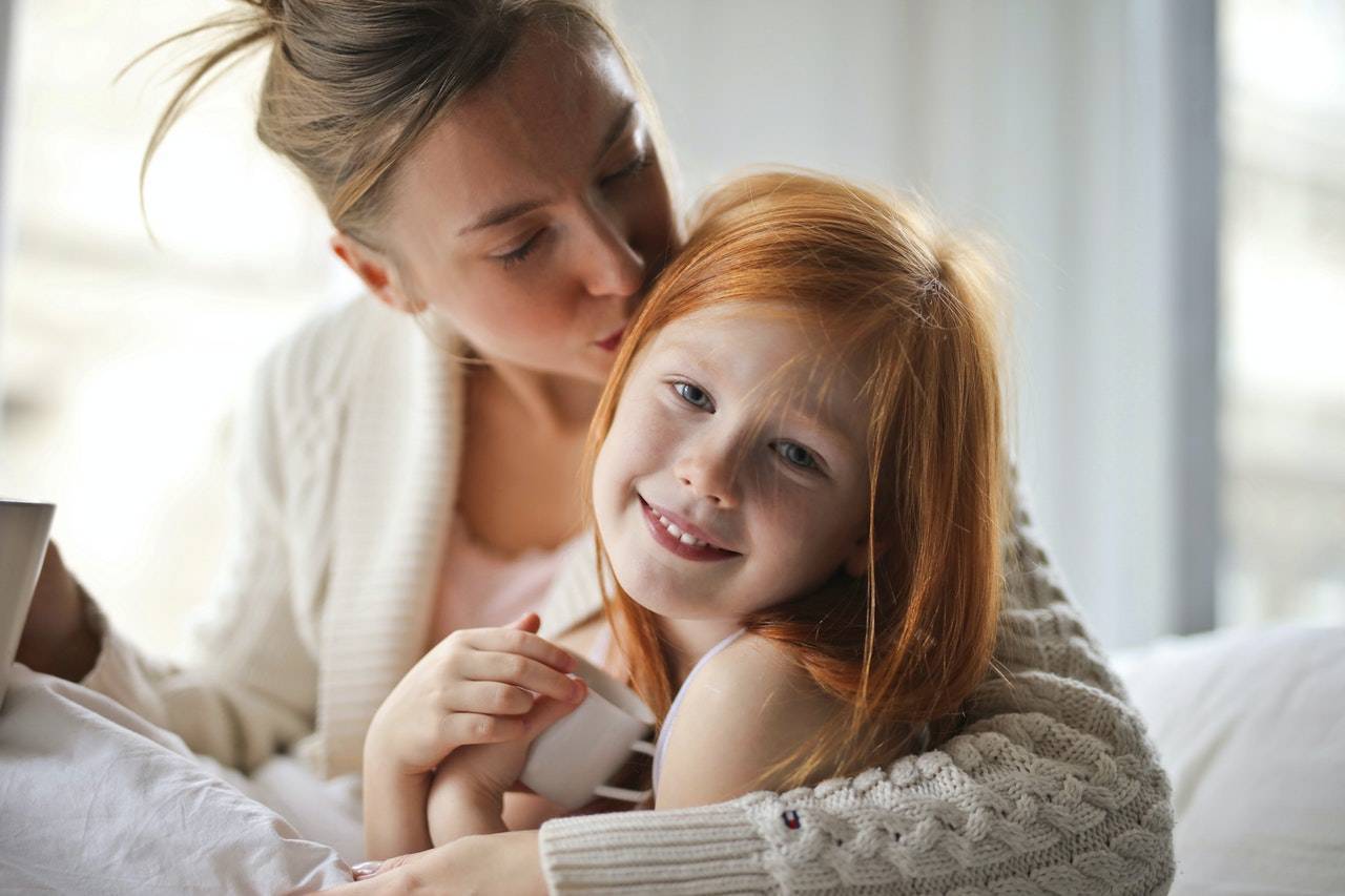 Mother kissing daughter