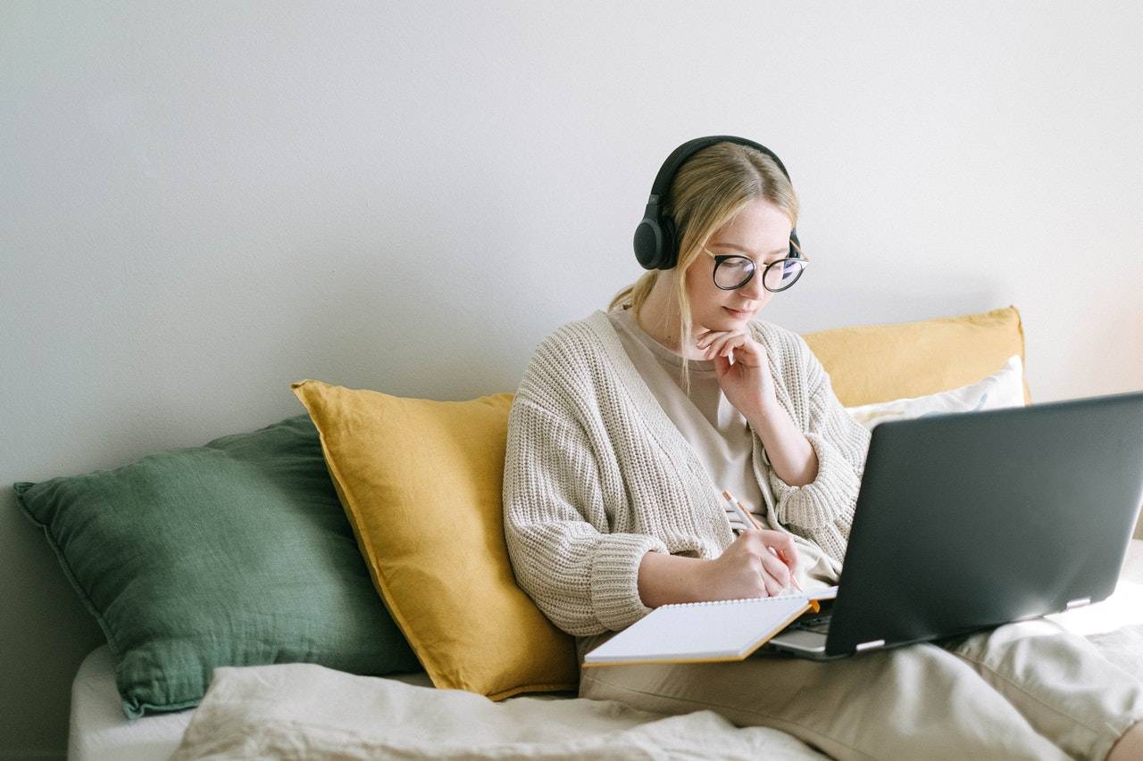 Young lady writing and holding a laptop