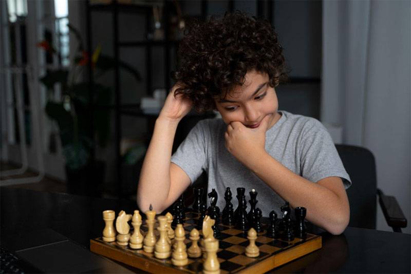 Child learning patience and focus while playing chess, developing critical thinking skills